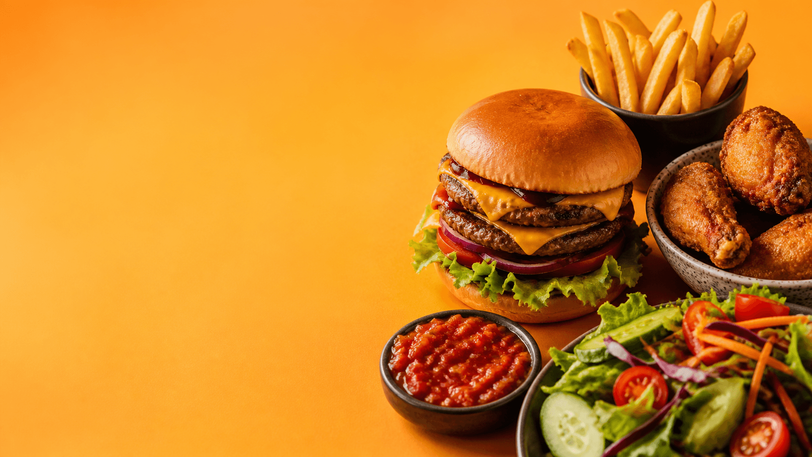 A burger, chips, chicken and fresh salad